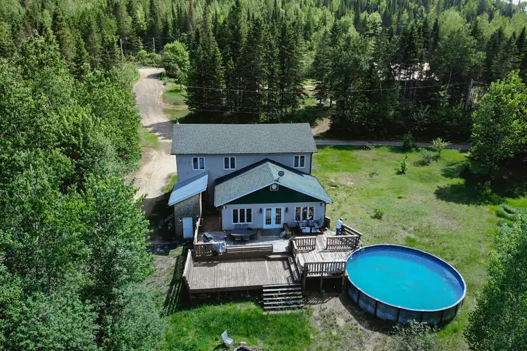 Vue aérienne d'une maison avec piscine entourée de forêt