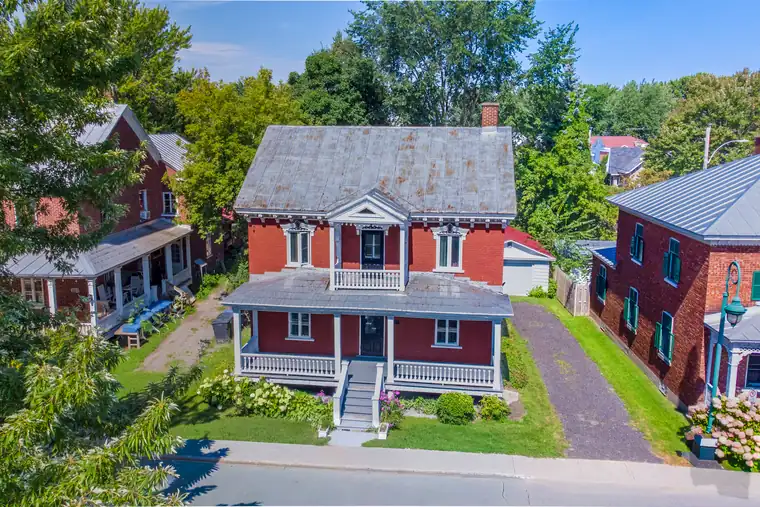 Maison ancestrale rouge avec galerie et toit en tôle