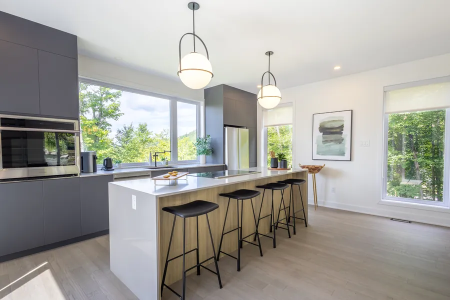 Cuisine moderne avec îlot de quartz, tabourets et armoires foncées