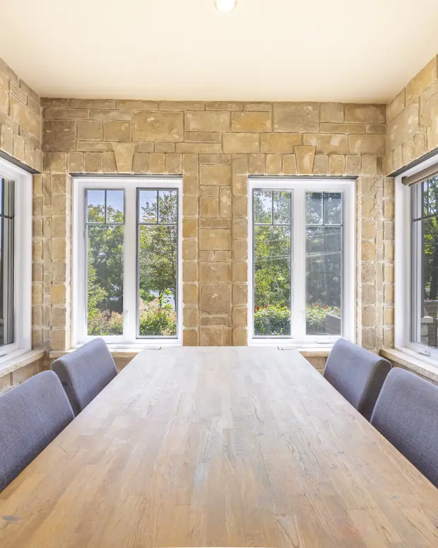 Salle à manger avec mur de pierre et fenêtres pleine hauteur