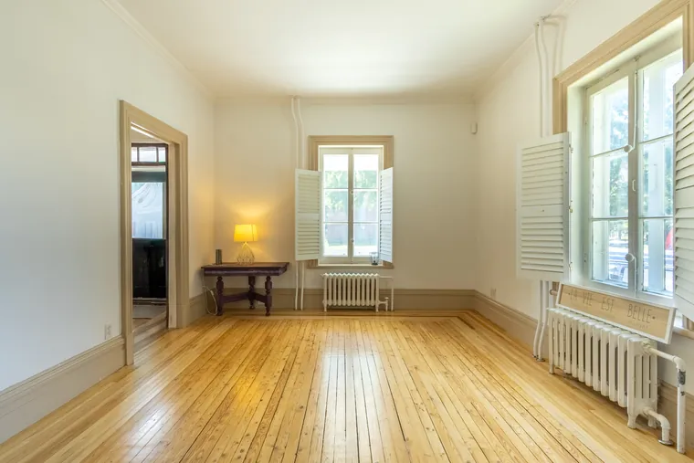 Salon vide d'une maison ancestrale, plancher de bois et grandes fenêtres